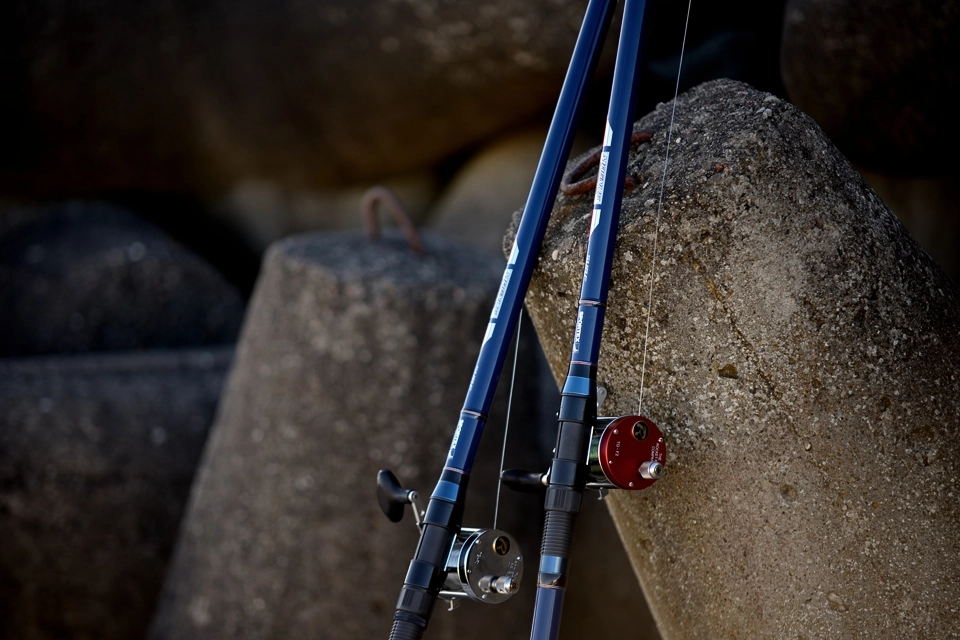 Kołowrotki i wędki morskie na tle umocnień betonowych