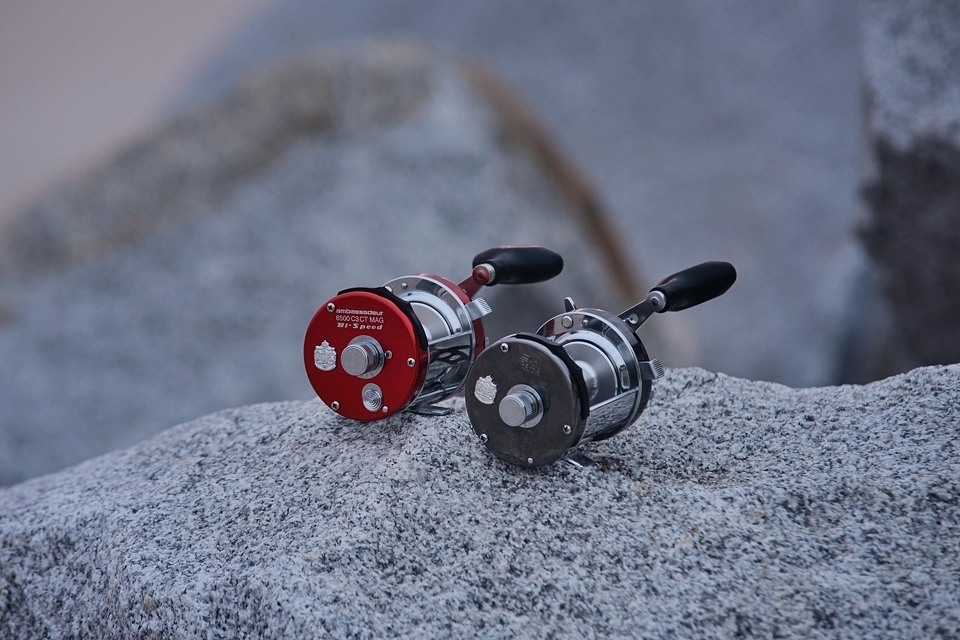 Fotografia dwóch kołowrotków o ruchomej szpuli stojących na skałach