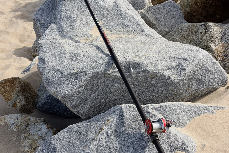 Wędka i ciężarek z ołowiu na tle morskiej kamienistej plaży