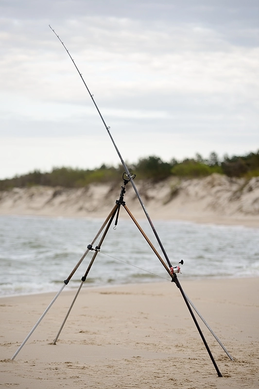 Wędka plażowa oparta o stojak wędkarski na tle morza