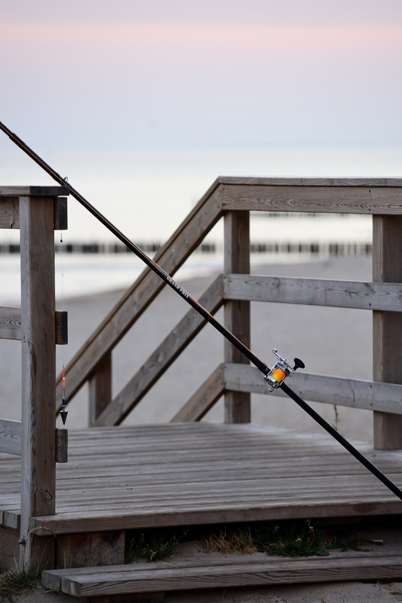 wędka plażowa na tle morza oparta o drewniane zejście na plażę