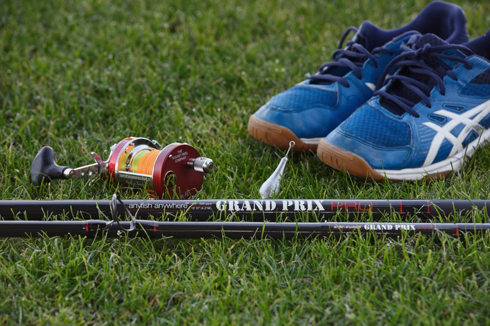 Wędka na trawie w otoczeniu kołowrotka ciężarka i butów sportowych