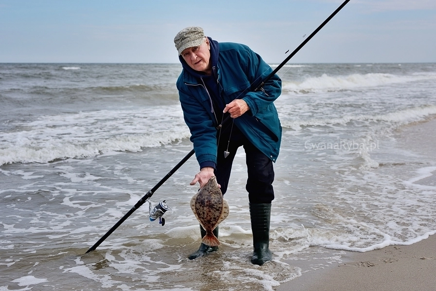 Wędkarz plażowy z wędką i flądrą