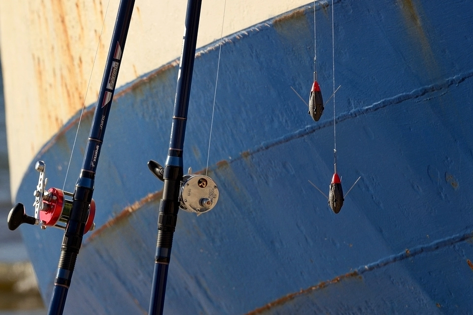 Wędki plażowe i ciężarki wędkarskie na tle burty kutra morskiego