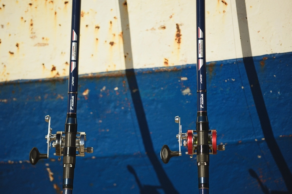 Wędki plażowe oparte o burtę starego kutra 