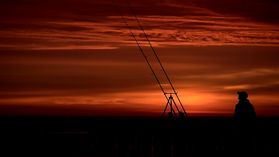 wędkarz morski na tle wschodu słońca