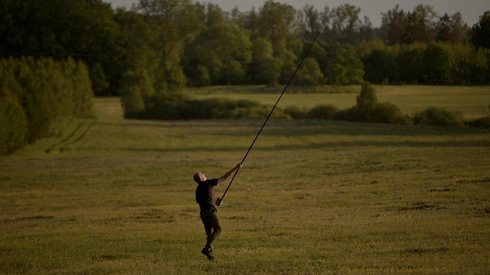 Sportowiec na trawie trzymający wędkę podczas rzutu